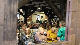 zdjęcie przedstawia publiczność zgromadzoną na teatrze przy stoliku.